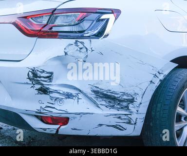 Detail mit tiefen Kratzern und schwarzem Farbübergang auf dem weißen Stoßfänger eines beschädigten Fahrzeugs Stockfoto