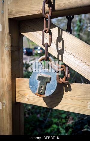 Rostiges Vorhängeschloss und Kette am Holztor Stockfoto
