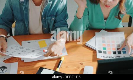 Nahaufnahme der Hände intelligenter Geschäftsteams, die die Farbpalette am Tisch betrachten, während sie Papier in die Luft werfen. Gruppe der Innenarchitektur spricht und diskutiert Stockfoto