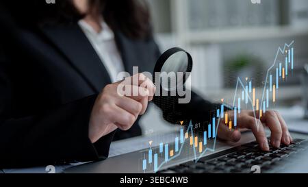 Ein Geschäftsexperte analysiert Finanzdaten mithilfe einer Lupe auf einem Notebook und zeigt die kritische Natur von Marktforschung und Investitionen Stockfoto