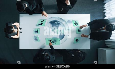 In einem modernen Büro arbeitet eine Gruppe von Fachleuten zusammen, die Nachhaltigkeitsziele diskutieren und gleichzeitig mit digitalen Grafiken auf der ganzen Welt interagieren Stockfoto