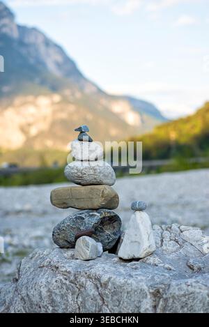 Ein Stapel Zen-Steine, die an einem felsigen Ufer mit Bergen im Hintergrund ausgeglichen sind. Das Konzept von Harmonie und Meditation. Stockfoto