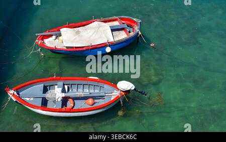 Blick von oben auf zwei kleine traditionelle Fischerboote, die in transparentem türkisfarbenem Wasser verankert sind und den Meeresboden in Giovinazzo Apulien, Italien, enthüllen Stockfoto