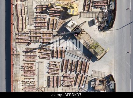 Luftaufnahme der Hochbahnbaustelle mit schweren Maschinen, gelbem Bagger, Stapeln von Baumaterialien und Arbeitern in Taiwan. Stockfoto