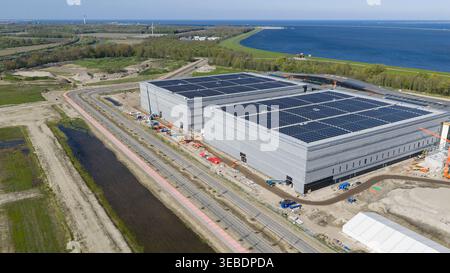 Luftaufnahme der JYSK DCL-Baustelle mit großen Industrielagern mit Solarpaneelen auf den Dächern in Küstennähe in Lelystad, Flevola Stockfoto
