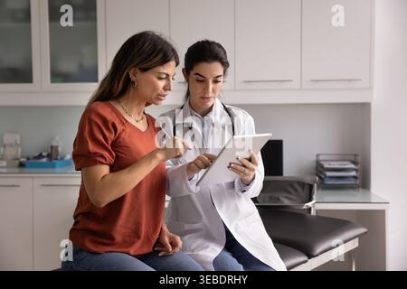 Weibliche Ärztin zeigt dem Patienten medizinische Informationen auf der Tablette Stockfoto