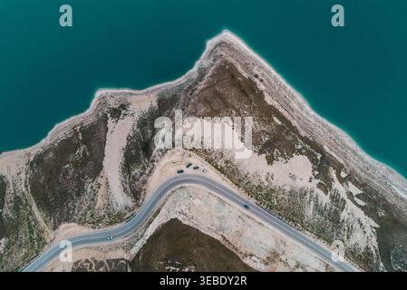 Aus der Vogelperspektive fängt die gewundene Straße ein, die die zerklüftete Küste des Kazenoy Sees mit blauem Wasser durchzieht Stockfoto