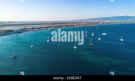 Aus der Vogelperspektive auf Segelboote vor Anker im türkisfarbenen Wasser des Poetto Strandes mit Salinen und Bergen im Hintergrund, Cagliari, Sardinien, Italien Stockfoto
