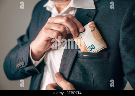 Nahaufnahme eines Mannes, der Euro-Bargeld in der Tasche versteckt, Geschäfts- und Finanzkonzept, Gehalt, Gewinn, Bestechung, persönliches Vermögen, oder wirtschaftlichen Erfolg. Wählen Sie Aus Stockfoto