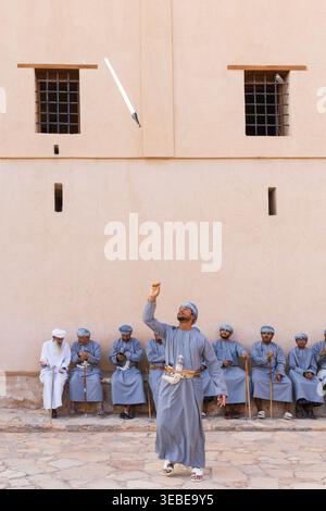 Ein Al-Razha-Künstler wirft sein Schwert in die Luft auf der Nizwa-Festung in Nizwa, Oman Stockfoto