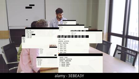 Führender bärtiger Indianer mit gestreiftem Hemd, der am Konferenztisch mit Code-Overlays präsentiert Stockfoto