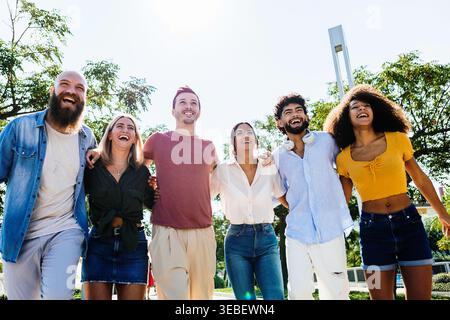 Multirassische Gruppe junger Freunde, die draußen spazieren und lachen Stockfoto