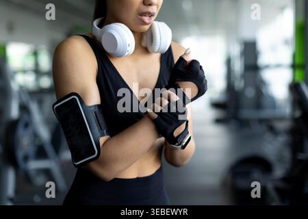 Junge Schwarze Frau im Fitnessstudio, die Handgelenkschmerzen hat, grimmig beim Arm hält Stockfoto
