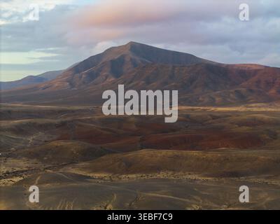 Aus der Vogelperspektive der vulkanischen Bergkette und der trockenen Wüstenlandschaft unter einem weichen bewölkten Himmel in Lanzarote, Kanarien, Spanien. Stockfoto