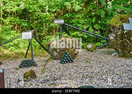 Eine historische militärische Darstellung im Freien in einem bewaldeten Gebiet mit Haufen von dunkelgrünen kugelförmigen Minen, die auf Kiesboden angeordnet sind, moosbedeckt Stockfoto