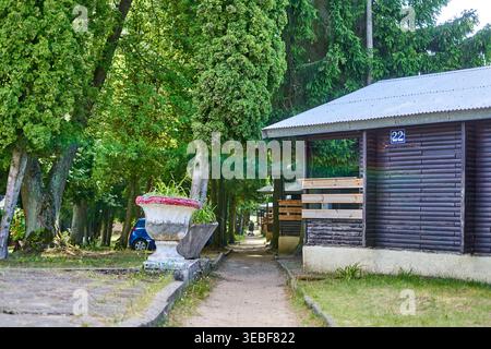 Ein malerischer Blick auf einen Ferienort oder Campingplatz mit dunklen Holzhütten mit horizontaler Blockhausverkleidung und Wellblechdächern. In der Stockfoto