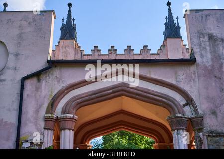 Eine detaillierte Ansicht eines neogotischen Architekturportals mit dreistufigen Spitzbögen, die von dekorativen Säulen mit Schnitzereien gestützt werden Stockfoto
