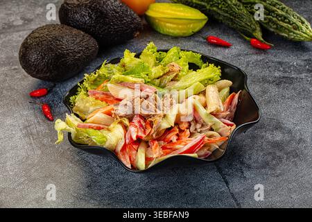 Appetitlicher Nudelsalat mit Thunfisch und Gemüse in einer cremigen Sauce. Die Top-Down-Ansicht auf dunklem Hintergrund hebt frische rote, grüne und beige Farben hervor. P Stockfoto