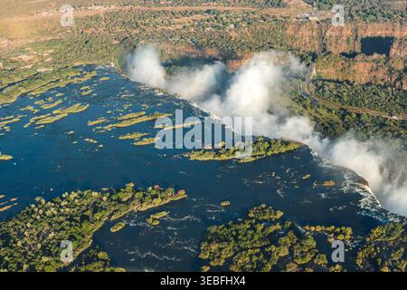 Simbabwe - Sambia - Victoria Falls - aus der Vogelperspektive sehen Sie den breiten blauen Sambesi-Fluss mit üppig grünen, bepflanzten Inseln direkt oberhalb von Victo Stockfoto