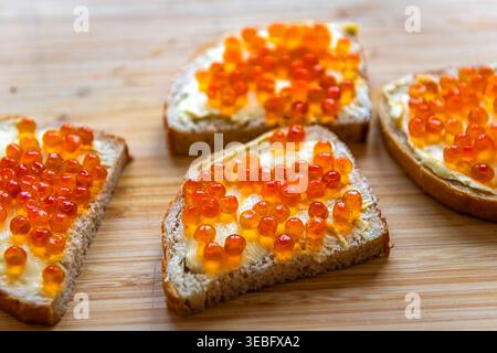 Brot Butter Sandwich Canape mit Lachskaviar Fisch Reh Essen auf hölzernem Schneidebrett Vorspeise Makronähe Stockfoto