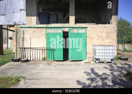 Teilweise offenes Tor einer Scheune unter einem Speicher, in einem verlassenen Herrenhaus auf dem italienischen Land Stockfoto