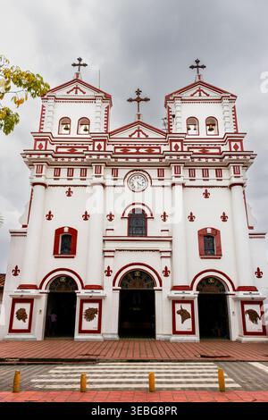Vorderansicht einer historischen weißen Kirche mit roten dekorativen Details in San antonio de Pereira, Kolumbien, zwei Glockentürmen, bogenförmigen Eingängen und einem Centra Stockfoto