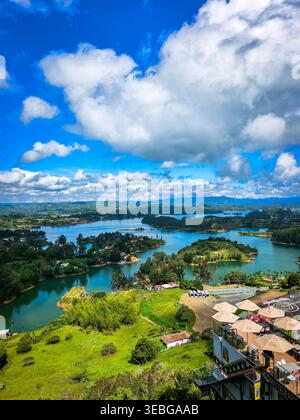 Malerischer Panoramablick auf den Stausee Peñol-Guatapé mit kleinen Inseln, üppigen grünen Hügeln und einem dramatischen bewölkten Himmel. Weite, erhöhte Landschaft Stockfoto