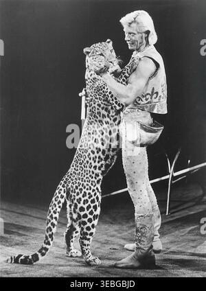 Werbefoto von Tiertrainer Gunther Gebel-Williams, der seinen Auftritt mit der 107. Ausgabe von Ringling Bros. Und Barnum & Bailey Circus – 1977 – promovierte. Von 1968 bis 1990 war er Superstar-Trainer für die Ringling Bros. Und Barnum & Bailey Circus. Bekannt für seine Arbeit mit Tigern, Elefanten und Leoparden, half er, einige der berühmtesten Spektakel des Zirkus zu kreieren. Seine energiegeladenen Auftritte machten ihn zu einem Namen und zu einem häufigen Gast in Fernsehsendungen wie der Ed Sullivan Show. Stockfoto