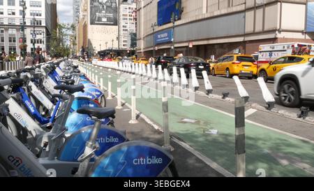 New York City, USA - 9. September 2024: Manhattan Midtown Street, 8 Avenue. Fahrradverleih in der Nähe von Penn Station, Madison Square Garden in Chelsea. Gelbes Taxiauto, städtischer Straßenverkehr, Leihfahrrad. Stockfoto