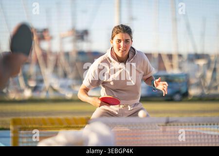 Junge Frau, die Tischtennis mit Fokus und Intensität spielt Stockfoto