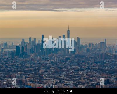 Aus der Vogelperspektive über die Dächer von Canarsie und Brooklyn in Richtung einer verdunkelten Skyline von Manhattan unter übereinander liegenden Winterwolken. Stockfoto