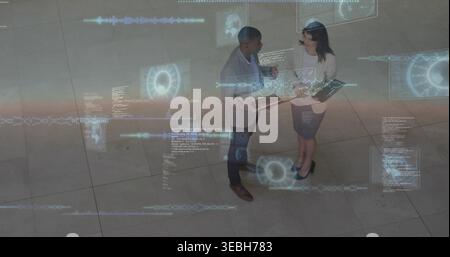 Gesten von zwei Kollegen, die Laptop und Tablet halten und AR-Daten in der Bürolobby in Business-Bekleidung diskutieren Stockfoto