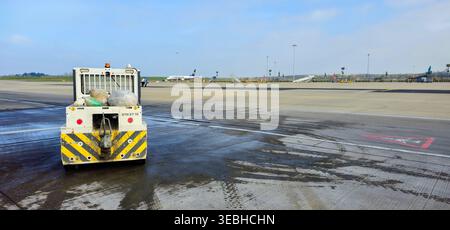 Ein Transport fährt über eine regenverseuchte Stansted-Vorfelde, ein paar Müllsäcke auf der Rückseite – den unglücklichen Maschinenraum eines Flughafens Stockfoto