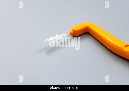 Makronaht einer winkligen Interdentalbürste isoliert auf Grau. Stockfoto