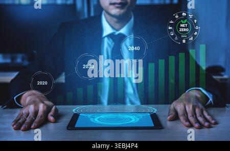Geschäftsmann analysiert digitale Trends auf einem Tablet und hebt Nachhaltigkeitsziele und Prognosen für Netto-Null-Emissionen bis 2020, 2030 und 2040 hervor Stockfoto