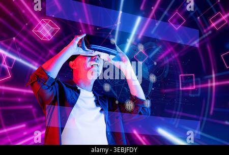 Ein junger Mann erkundet freudig eine digitale Welt mit einem Virtual-Reality-Headset, umgeben von lebendigen Grafiken, die moderne Netzwerke und darstellen Stockfoto
