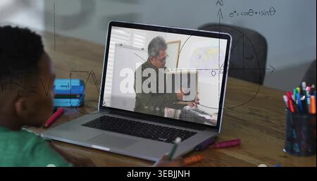 Zeigt den Laptop, der den Tutor zeigt, der auf das Brett auf dem Tisch zeigt, und das Kind in einem grünen Hemd, das den Bleistift hält Stockfoto
