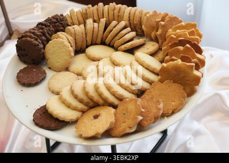 Cookies variieren in Form, Größe und Farbe. Süße Leckereien, die einladend zum Teilen arrangiert werden. Sanfte Beleuchtung verstärkt Gold- und Brauntöne. Ideal für Kulinare Stockfoto