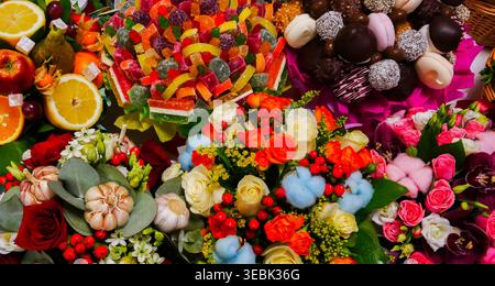 Orangen, Erdbeeren und Schokoladentrüffel sorgen für süßen Charme. Helle Blüten umgeben das Sortiment mit fröhlicher Energie Stockfoto