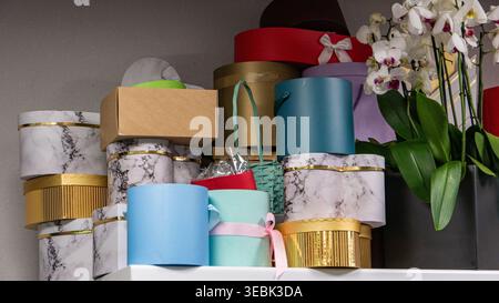 Pastellfarbene Bänder und Geschenktüten sorgen für Charme. Weiße Orchideen umrahmen die Komposition sanft. Ruhige, elegante und festliche Stimmung dominiert die Szene Stockfoto