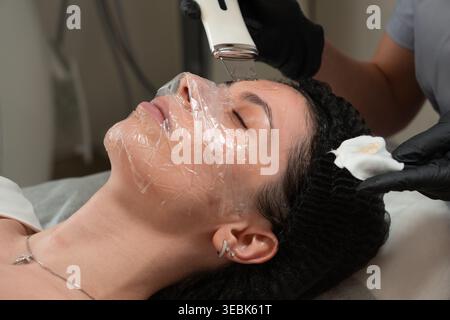 Nahaufnahme eines Kosmetikers, der Ultraschallgesichtspeeling an junger Frau in der Schönheitsklinik durchführt. Professionelle Hautpflege mit Ultraschall-devi Stockfoto