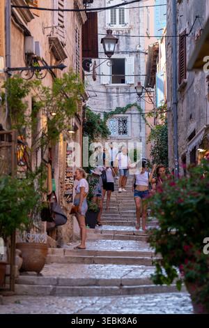 Rovinj, Kroatien - 16. August 2025: Eine vertikale Aufnahme, die die lebhafte Atmosphäre einer historischen europäischen Gasse einfängt. Warmes, natürliches Tageslicht Stockfoto