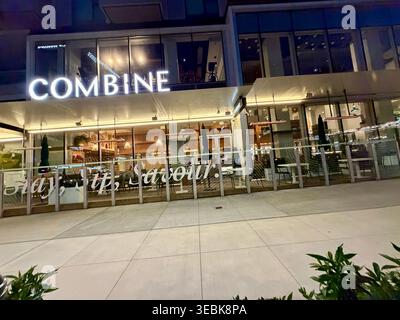 Surrey, BC, Kanada - 26. April 2026: Die beleuchtete Fassade des Combine Cafe bei Nacht mit moderner Glasarchitektur und 'Stay, SIP, Savor'-Tex Stockfoto