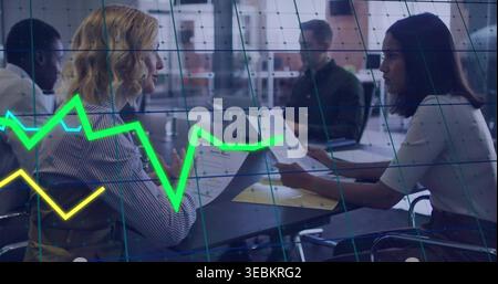 Prüfung von zwei Frauen in Business Casual, Vergleich von Berichten am Bürotisch mit Laptop, Diagramm-Overlay Stockfoto