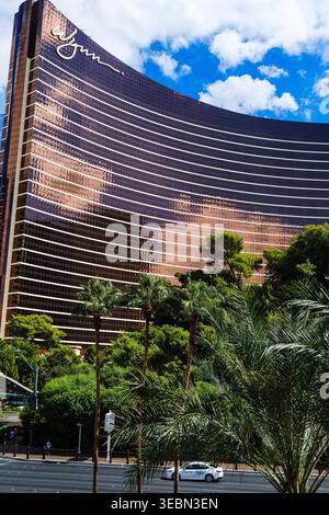 Das Wynn Las Vegas Hotel und Casino am Las Vegas Strip, umgeben von Palmen und tropischem Grün unter einem hellblauen Himmel. Stockfoto
