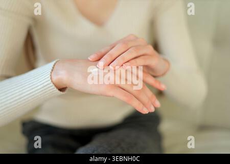 Handcreme Für Weiche Haut Auftragen. Nahaufnahme einer jungen Frau, die Feuchtigkeitscreme auf ihre Hände aufträgt und Hautpflege, Hygiene und tägliche Selbstpflege zeigt Stockfoto