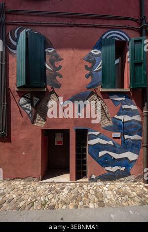 Bologna, Italien - 26. März 2022: Blick auf lebendige Straßenkunst mit zwei gegenüberliegenden Figuren auf einer strukturierten Wand, eingerahmt von offenen grünen Fensterläden und einem Stein Stockfoto