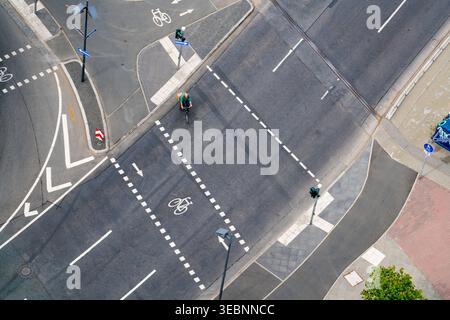 Frankfurt am Main, Deutschland - 13. April 2017: Blick auf eine geschäftige urbane Kreuzung von oben, ein Radfahrer, der auf einer dunklen A stark weißen Straßenmarkierung fährt Stockfoto