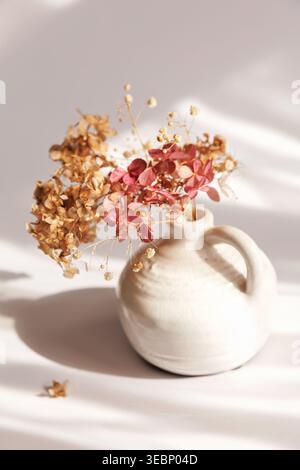 Minimal herbstlich getrocknete Hortensie in weißer Keramikvase Stockfoto