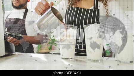 Der Barista wird in eine gestreifte Schürze gegossen, um eiskalten Espresso an der Theke zu machen, mit Pitcher und Gläsern Stockfoto